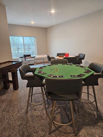 A poker table surrounded by chairs in a room.